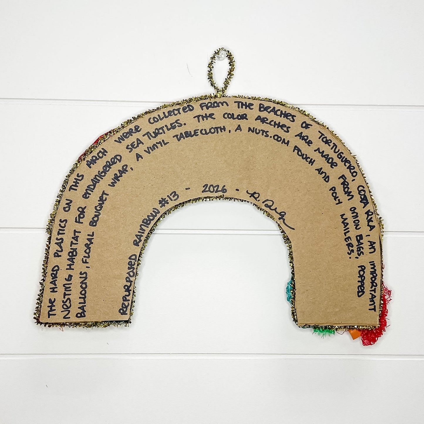 Cardboard rainbow with text and colorful ends on a white wooden background