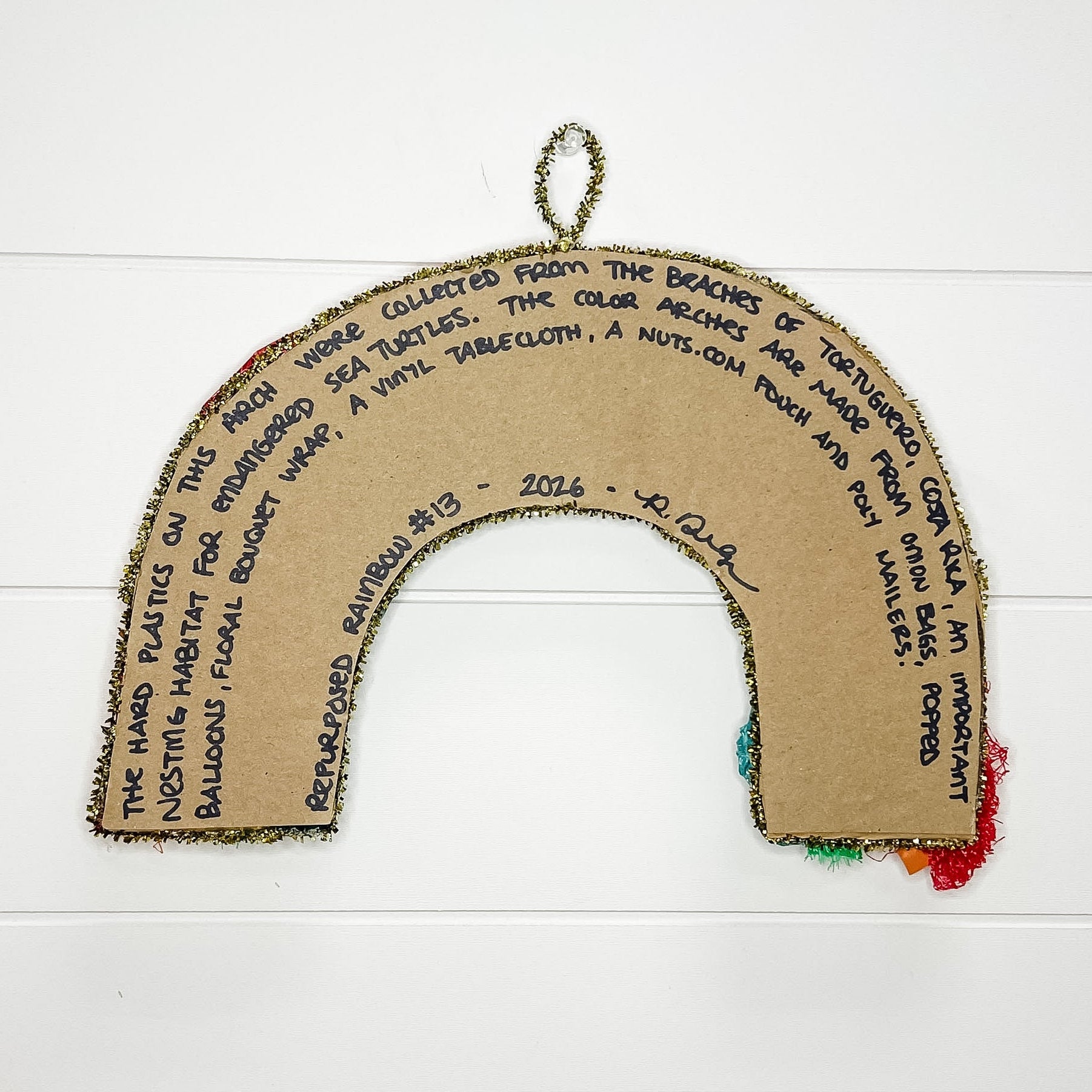 Cardboard rainbow with text and colorful ends on a white wooden background