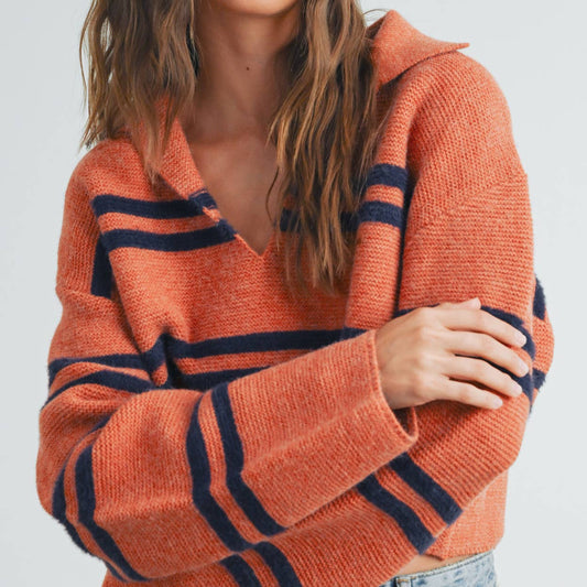 Woman wearing an orange sweater with blue stripes against a white background